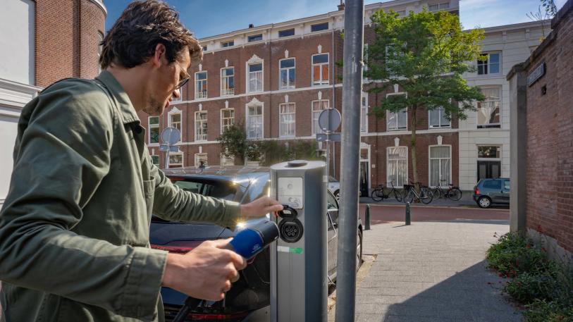 Man laadt elektrische auto in de straat bij publieke laadpaal Velian