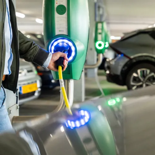 man staat te laden in overdekte parkeergarage